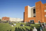 Several people sitting on the Campus of Santiago next to the library.